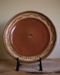 A large terracotta plate with decorative border